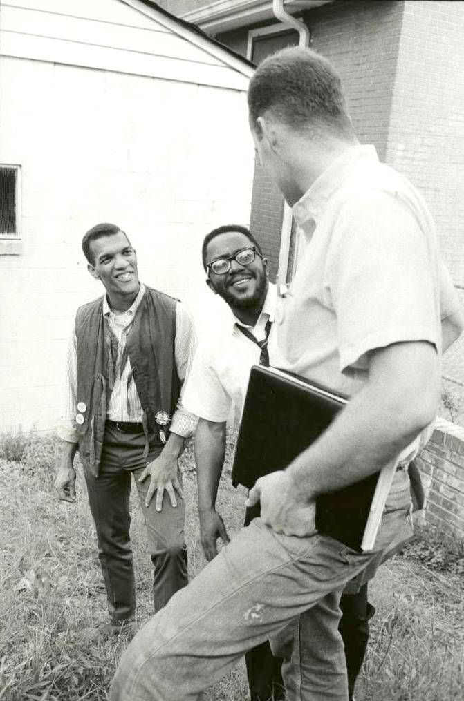 Three men standing on steps talking and smiling.